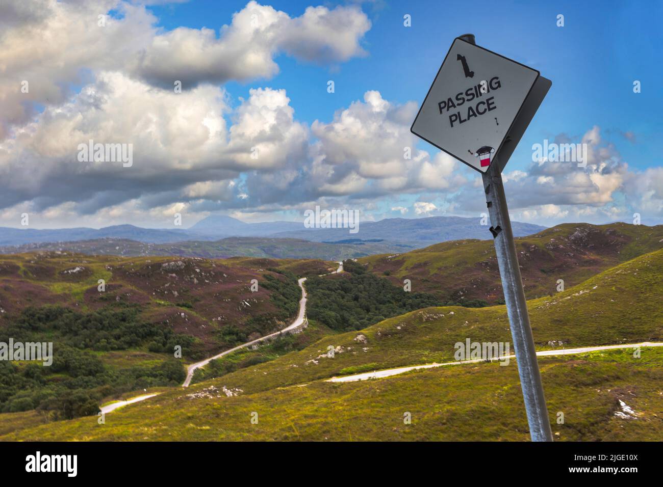 Un panneau routier en forme de diamant blanc avec les mots 'PASSING PLACE' écrit en noir, contre un ciel bleu avec des nuages, Banque D'Images