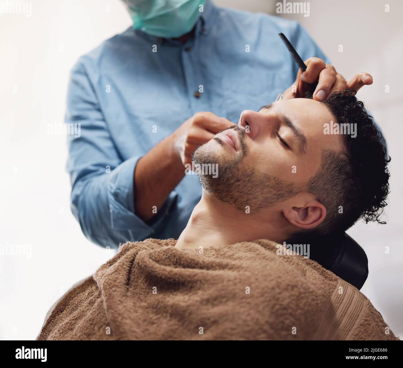 Il s'est taillé les cheveux et la barbe. Un beau jeune homme s'est entretenu par un barbier. Banque D'Images