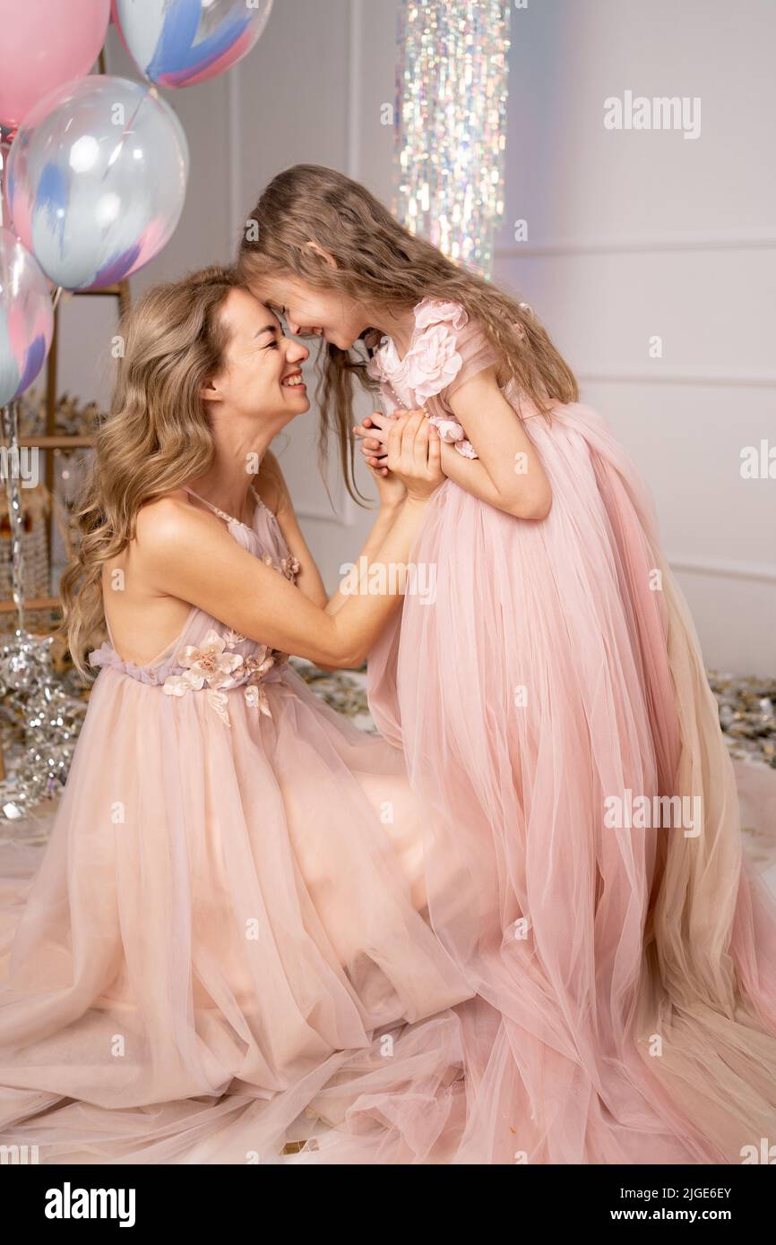 charmante gaie et mignonne mère et fille dans de belles robes longues sont embrassant, appréciant les vacances, ballons, surprise, cadeau, ambiance de vacances. B Banque D'Images