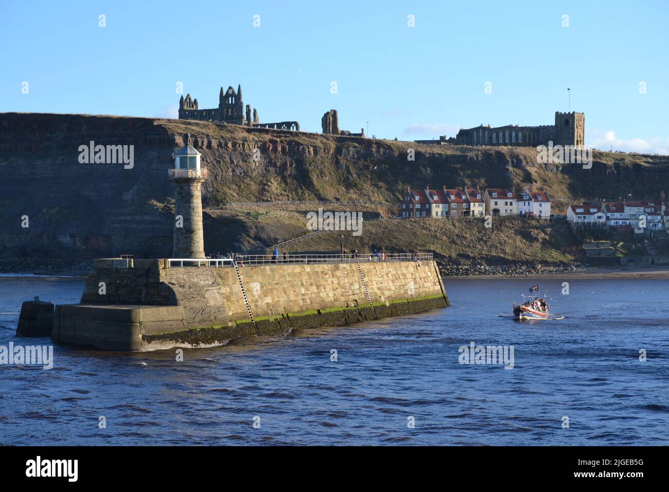 Excursions en bateau de plaisance Old Lifeboat quittant le port de Whitby par Une journée ensoleillée avec l'abbaye de Whitby et l'église St Marys au-dessus du mur du port - North Yorkshire - Royaume-Uni Banque D'Images