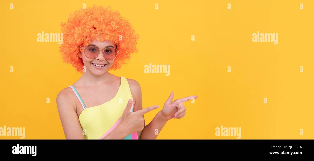 enfant portez des lunettes de soleil et un maillot de bain. jeune fille avec un doigt de pointage de cheveux orange. Adolescent drôle sur la fête, affiche en-tête de bannière avec espace de copie. Banque D'Images