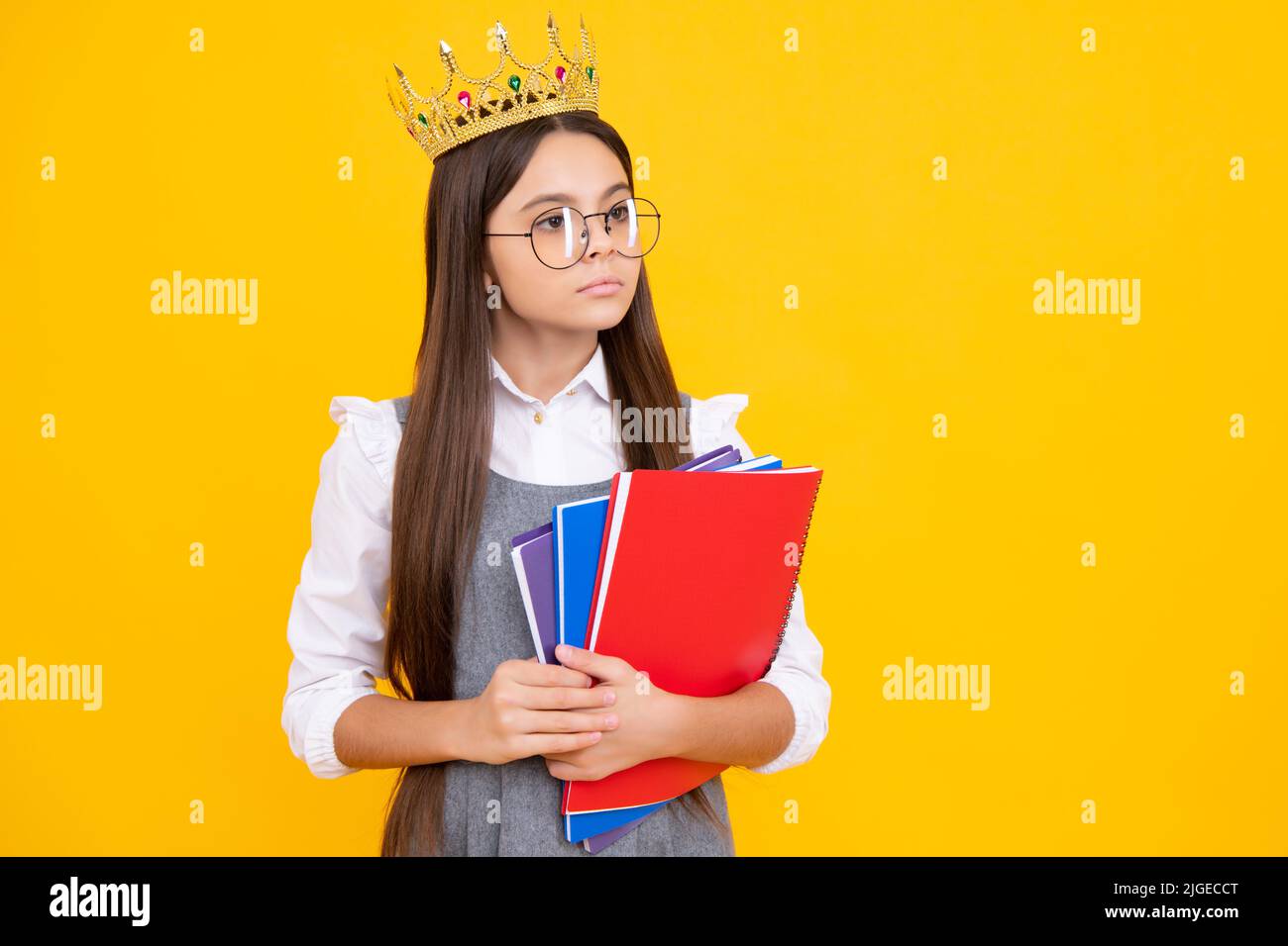 Écolière nerd princesse en uniforme scolaire et couronne célébrant la victoire sur fond jaune. École garde d'enfants livre. Diplôme d'éducation, victoire Banque D'Images