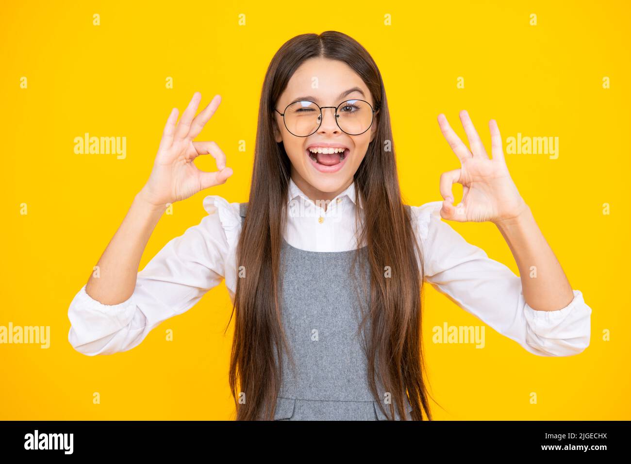 Jeune fille enfant montrer les doigts ok symbole langue signe isolé sur fond jaune. Drôle de visage d'adolescent. Visage excité. Expression stupéfaite, gaie Banque D'Images