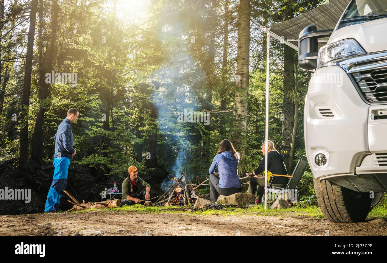 Quatre amis blancs adultes dans leur 40s pending dehors à côté de Campfire pendant le Wilderness Boondocking camper Camping Banque D'Images