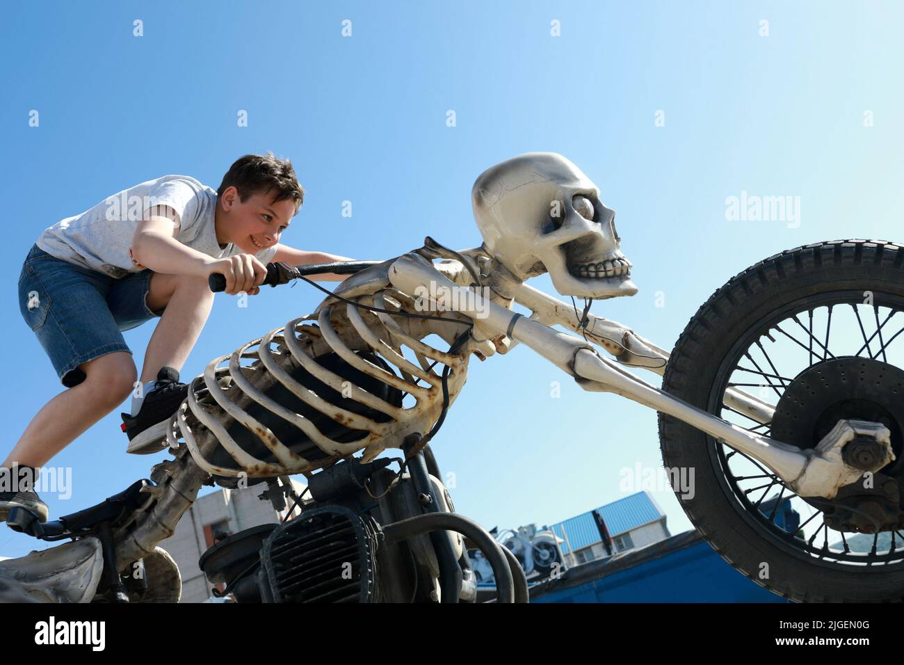 Portrait d'un garçon debout sur une moto sous forme de squelette Banque D'Images