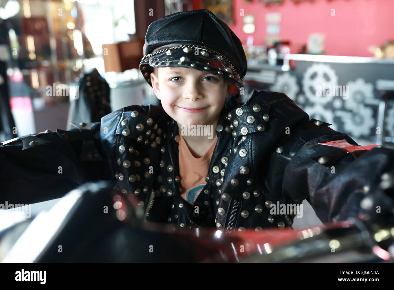 Portrait d'un enfant heureux dans une veste en cuir et une casquette sur la moto Banque D'Images