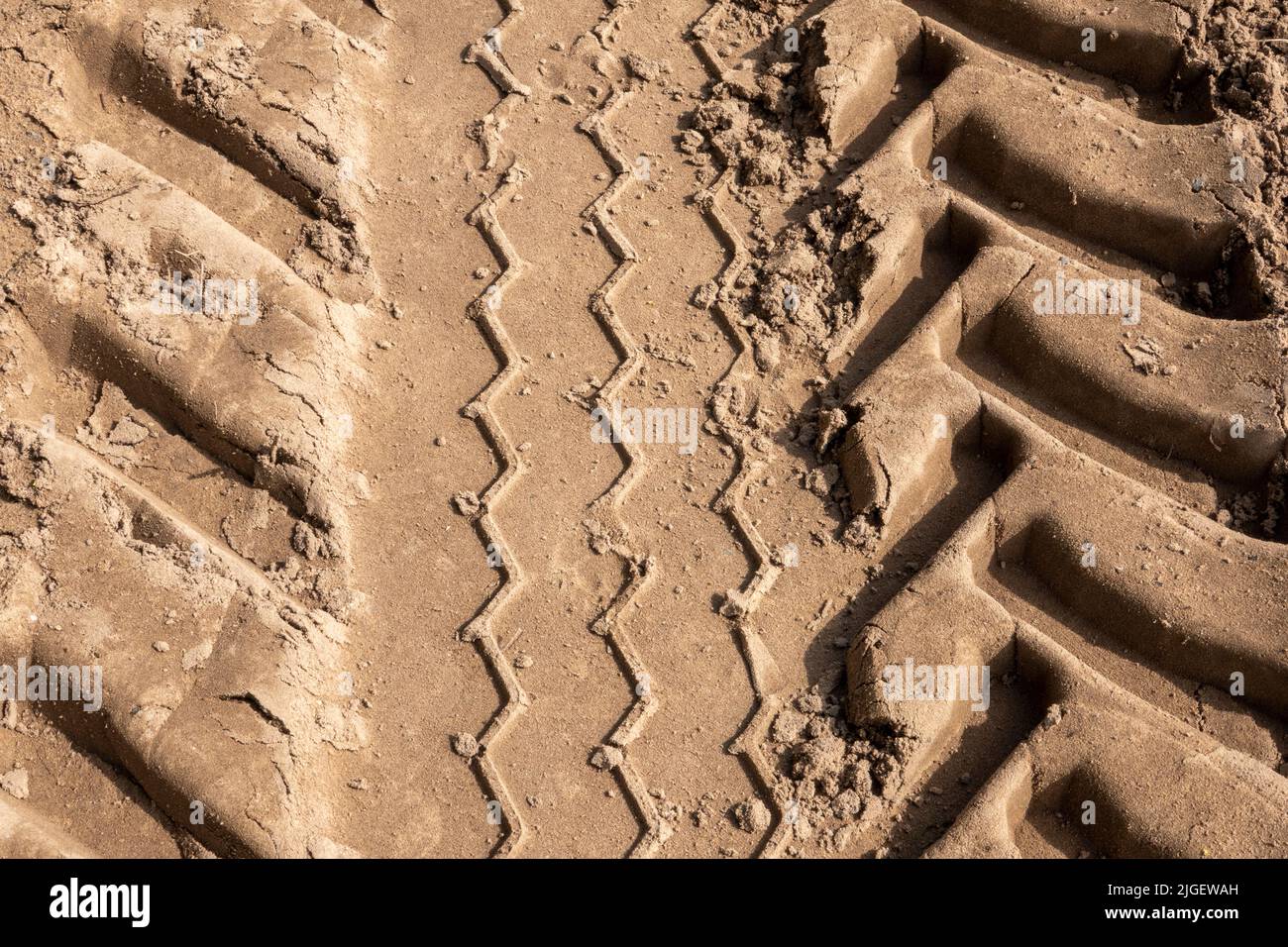 Chenilles de pneus de tracteur lourd dans du sable mou avec des crêtes profondes Banque D'Images