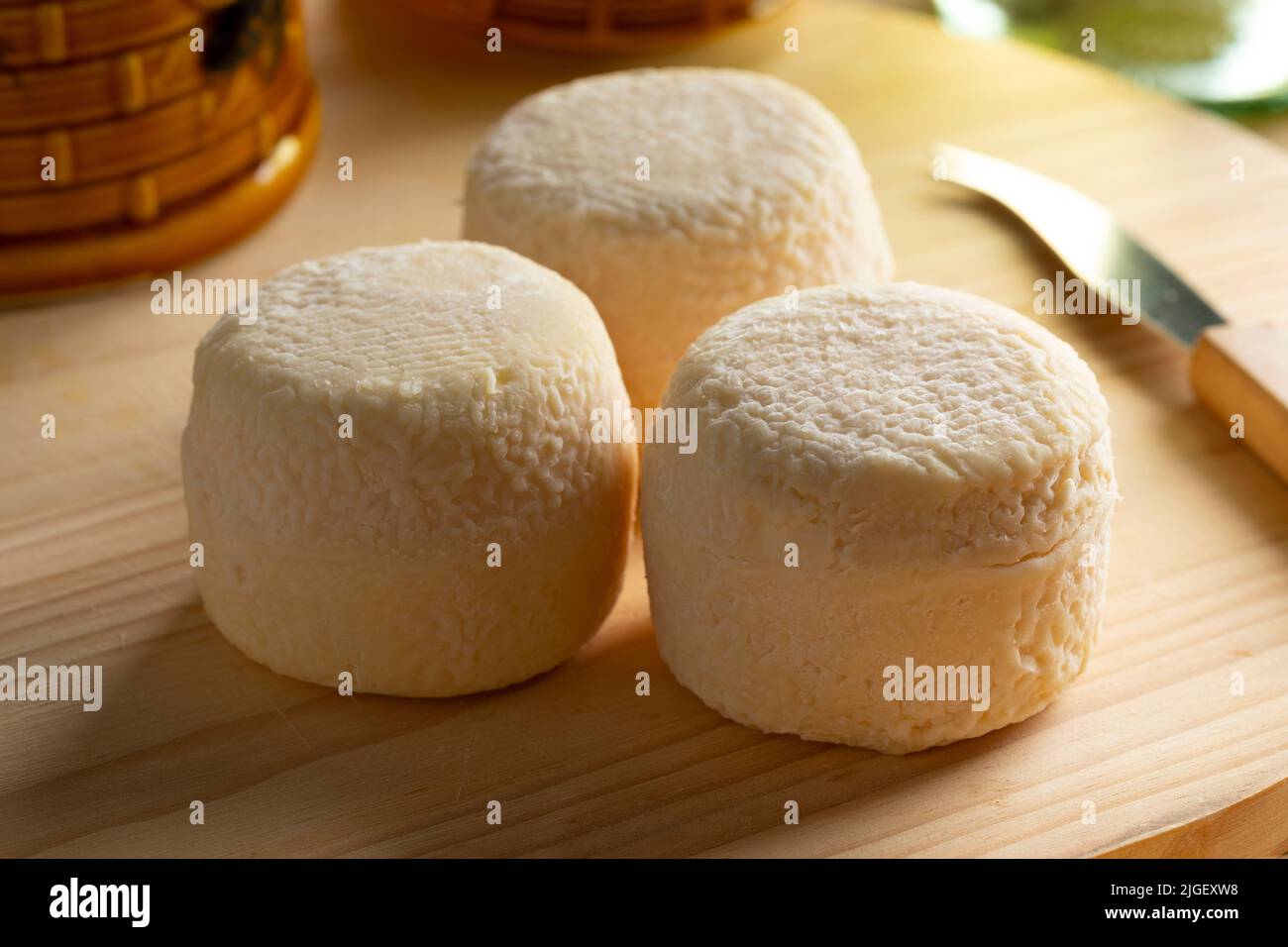 Trois petits fromages de chèvre entiers français traditionnels sur une planche à découper en gros plan Banque D'Images