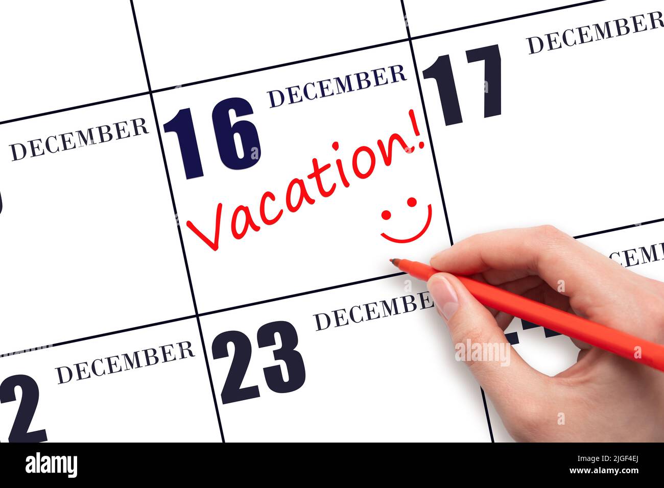 16th jour de décembre. Une main écrivant un texte DE VACANCES et dessinant un visage souriant sur une date calendaire 16 décembre. Concept de planification des vacances. Mont d'hiver Banque D'Images