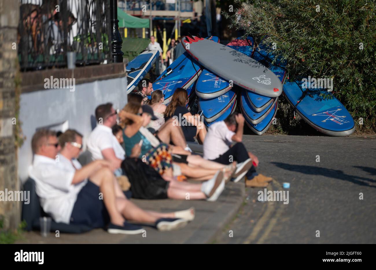 Londres, Royaume-Uni. 10th juillet 2022. Les amateurs de pub s'assoient au soleil devant un tas de paddleboards sur la Tamise. Credit: Sebastian Gollnow/dpa/Alay Live News Banque D'Images