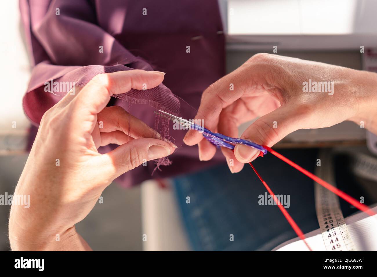 vue aérienne des mains coupant des fils à partir d'un morceau de tissu avec des ciseaux Banque D'Images