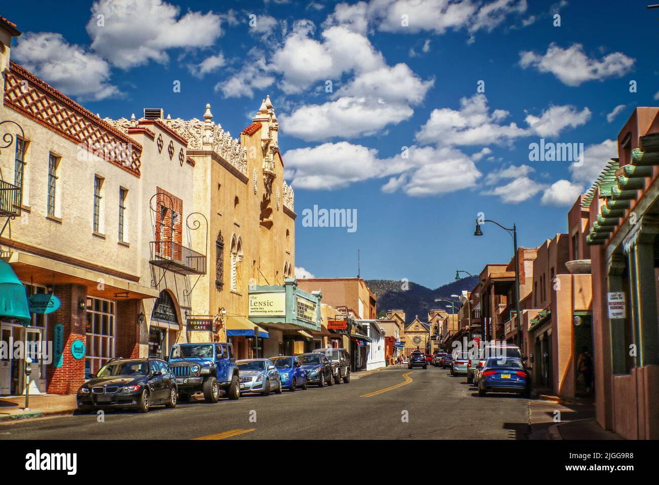 07-17-2017 Santa Fe Nouveau-Mexique USA - rue du centre-ville avec l'architecture Adobe Santa Fe emblématique et des voitures garées des deux côtés avec des montagnes à l'arrière-plan Banque D'Images