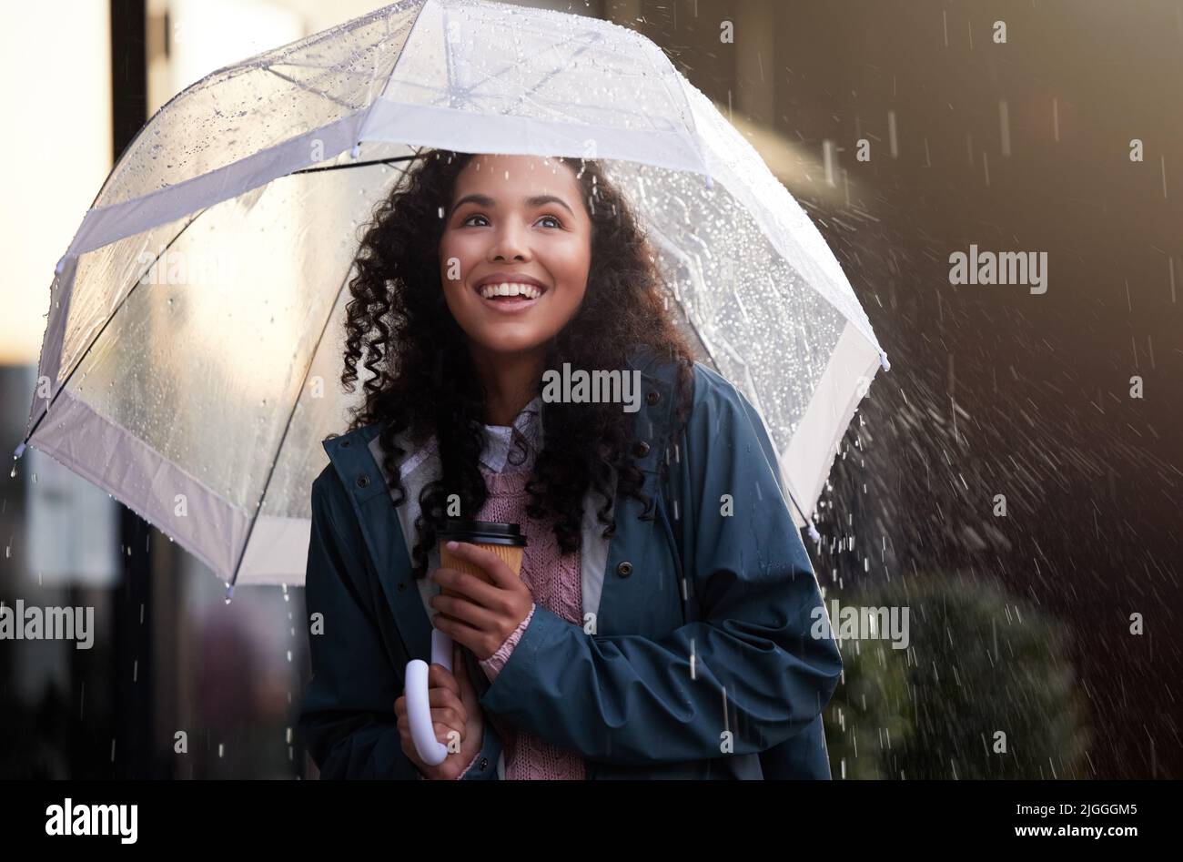 La pluie est une bénédiction d'en haut. Une jeune femme admirant la pluie dans la ville. Banque D'Images