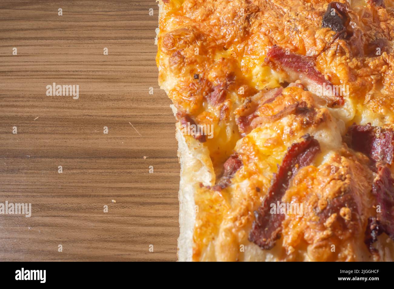 Focaccia italien fraîchement cuit avec du fromage jaune et du pastrami, dans un comprimé en bois avec espace de copie laissé. Banque D'Images