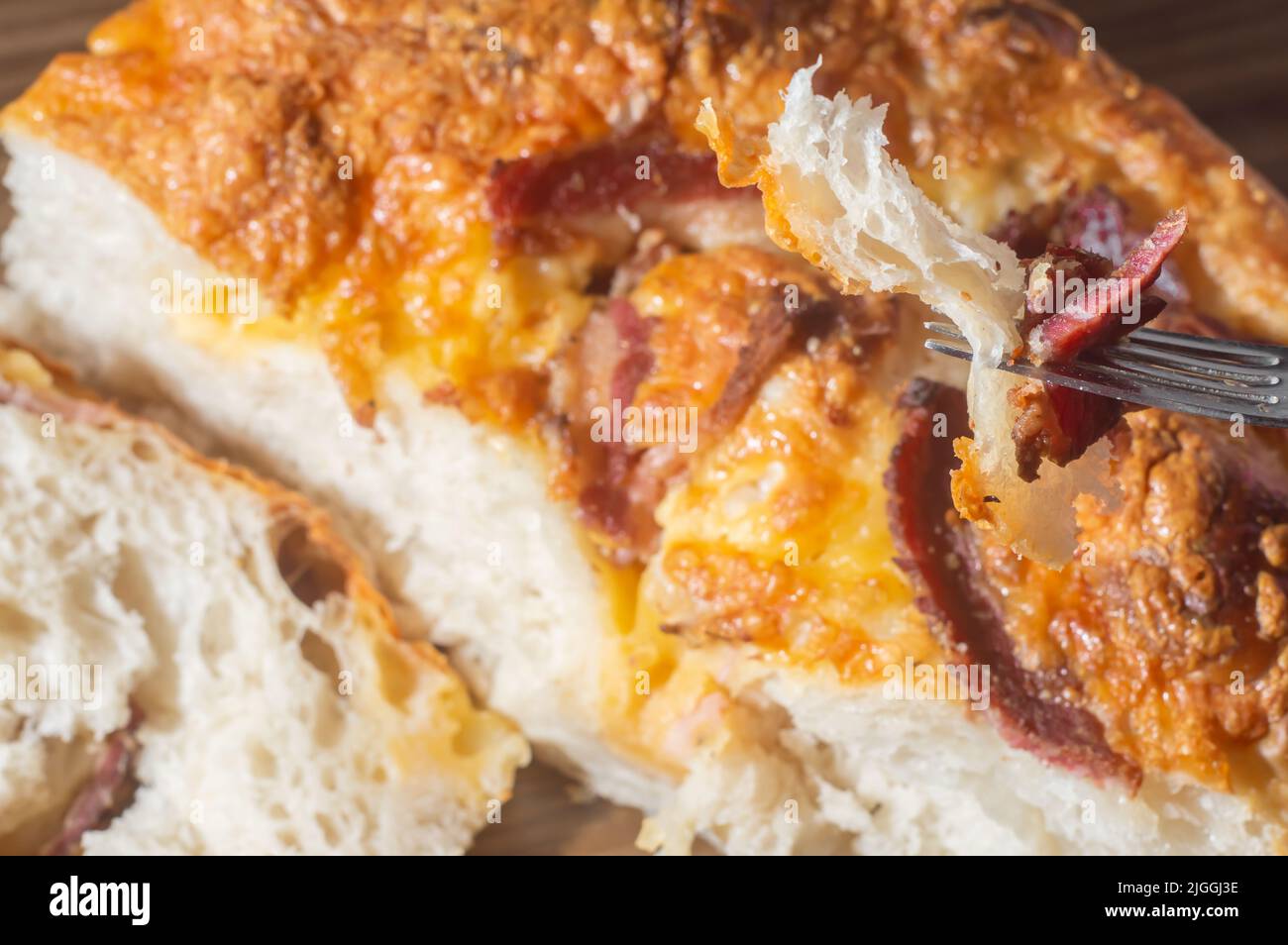 Focaccia italien fraîchement cuit avec du fromage jaune et du pastrami, dans un comprimé en bois avec espace de copie laissé. Banque D'Images