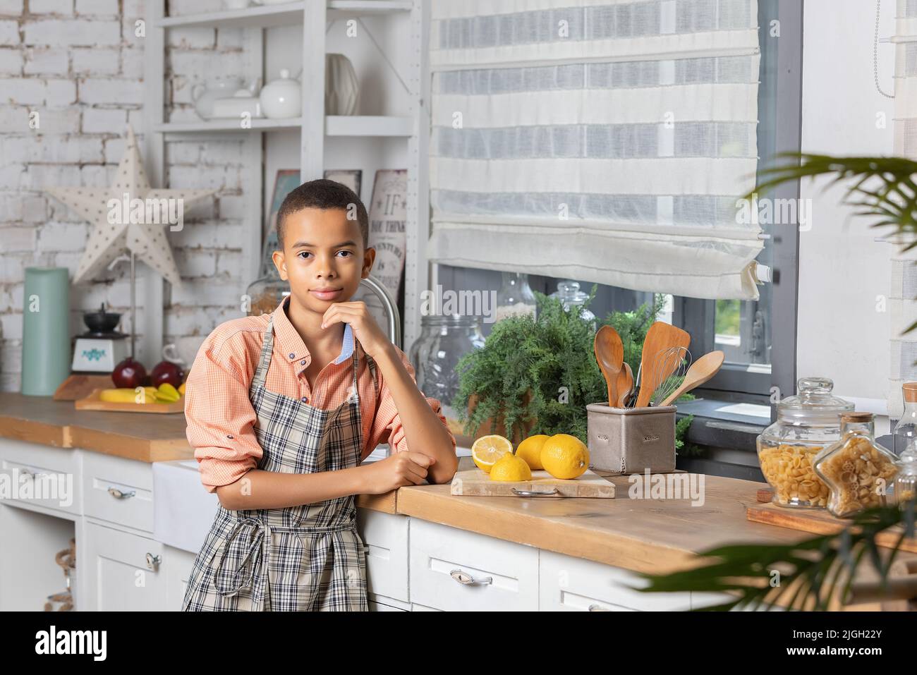 Enfant noir cuisant du citron frais dans la cuisine à la maison. Enfant africain se préparant sur la table. Banque D'Images
