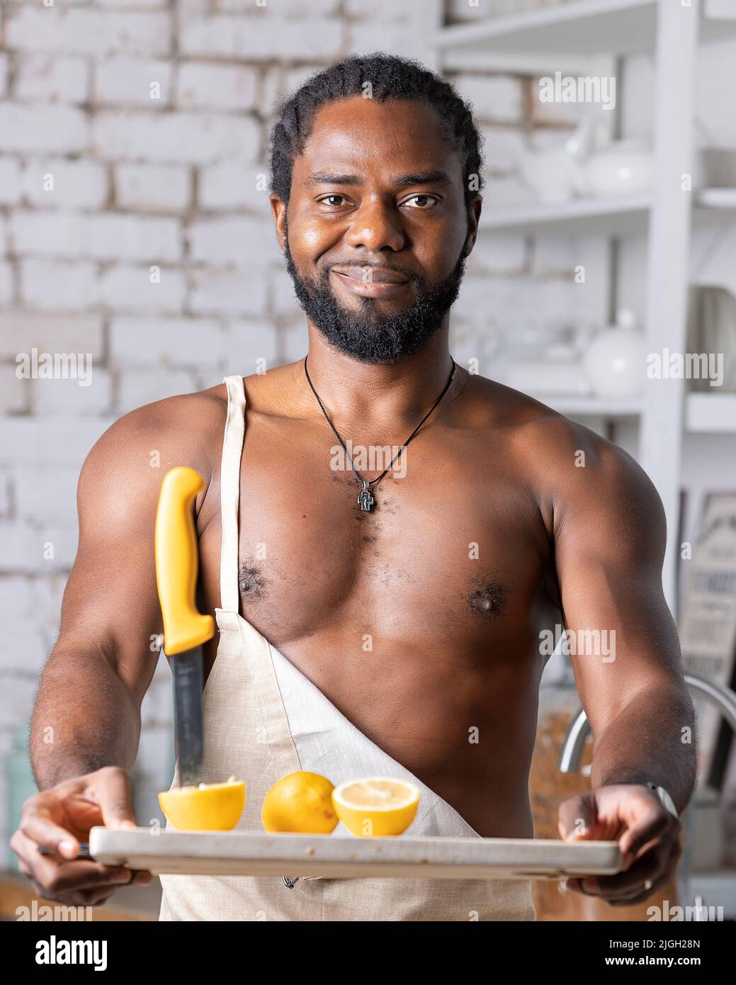 Un homme noir prépare un petit-déjeuner ou un déjeuner dans la cuisine à la  maison. Homme afro-américain portant un tablier préparant le citron Photo  Stock - Alamy