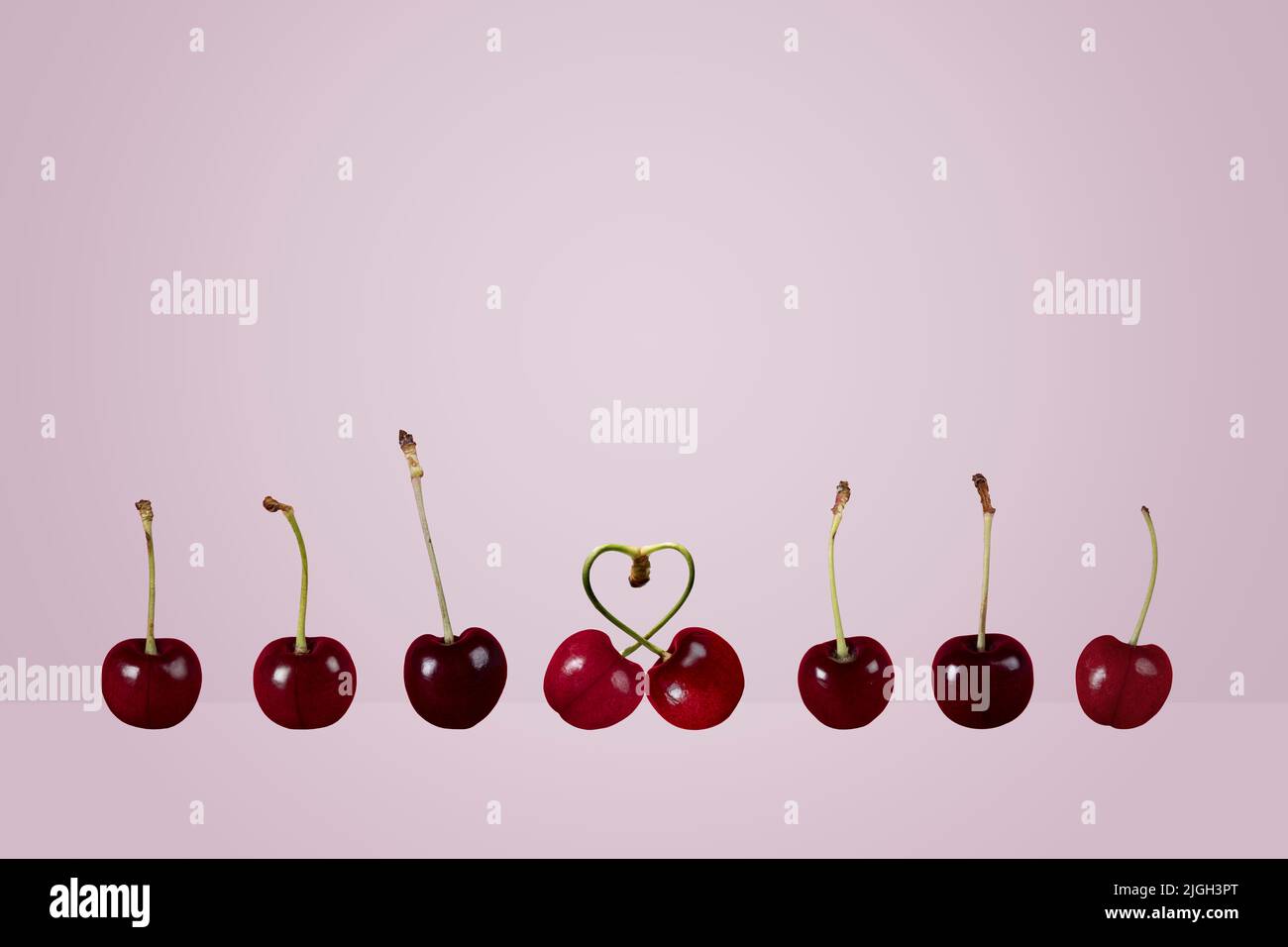 couple simple couples concept rangée de cerises mûres paire coeur cerises fruit sur un fond coloré lilas lavande Banque D'Images