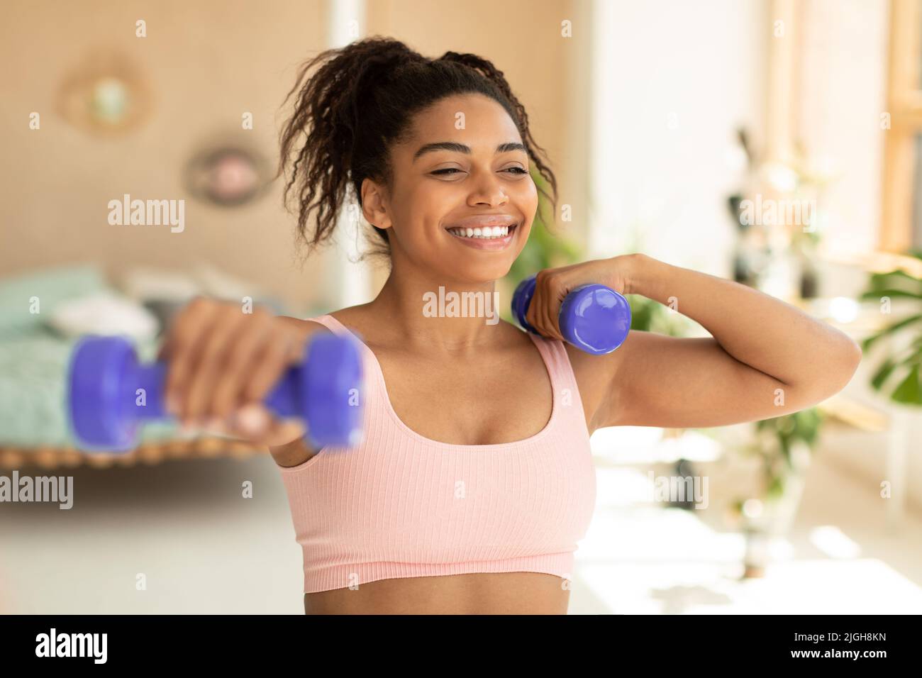 Entraînement avec poids. Bonne femme afro-américaine faisant des exercices avec des haltères, renforçant son corps à la maison Banque D'Images