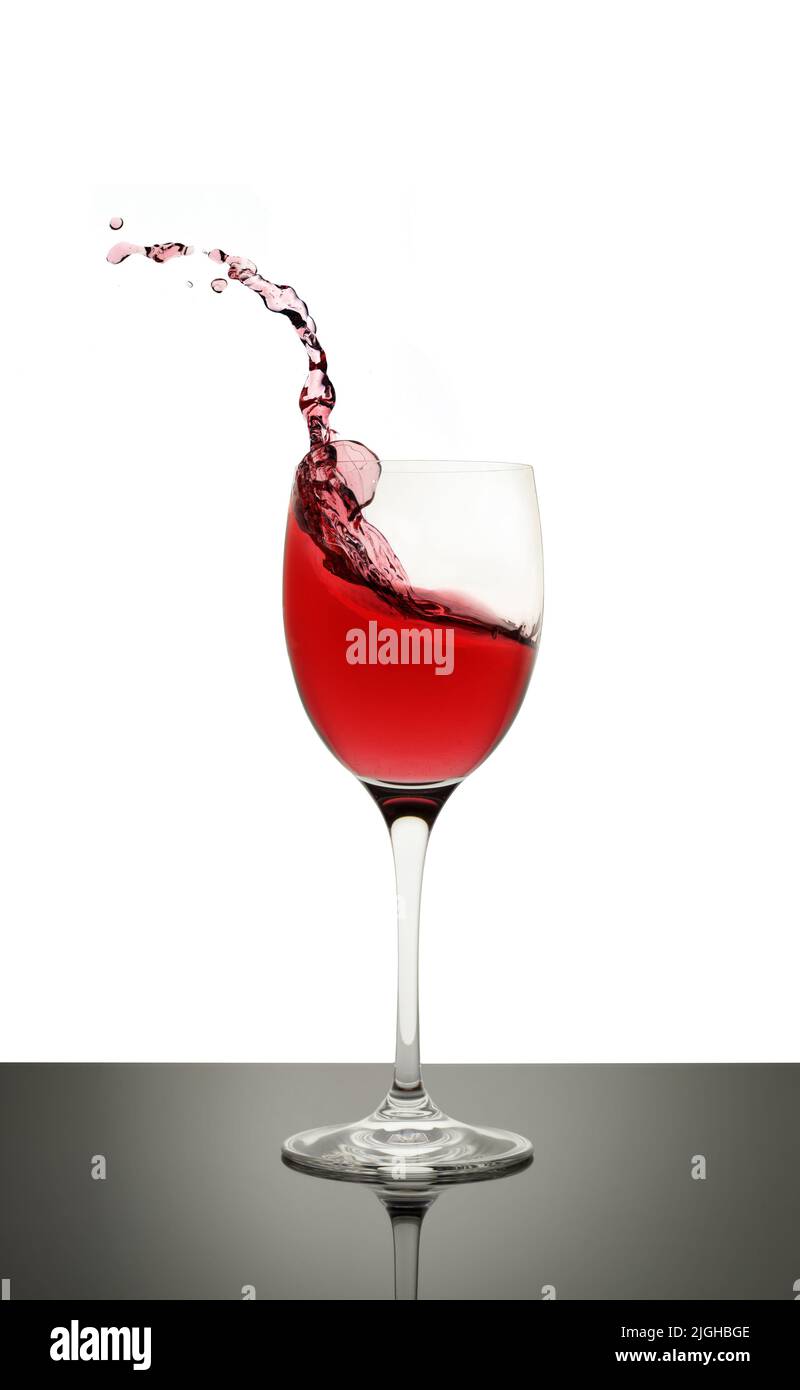 le vin rouge éclabousse dans un verre à tige Banque D'Images