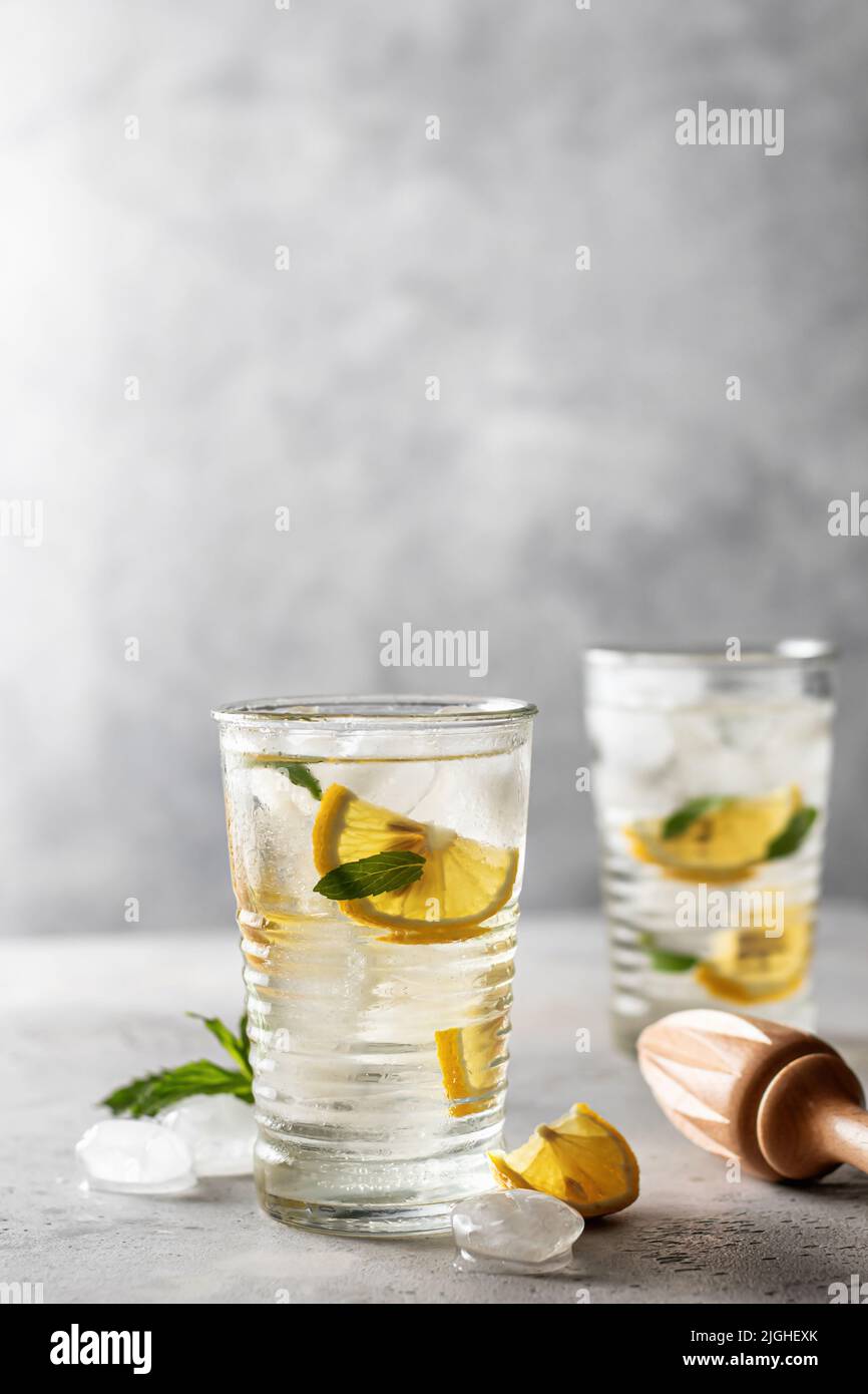 Limonade ou cocktail mojito avec centrifugeuse au citron, à la menthe et en bois, boisson rafraîchissante glacée d'été sur fond gris. Orientation verticale Banque D'Images