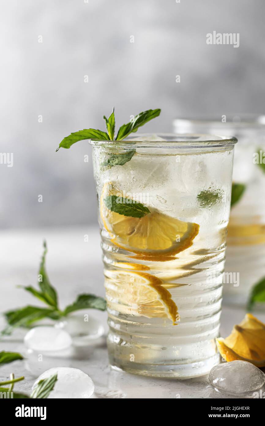 Limonade ou mojito cocktail au citron et à la menthe, boisson rafraîchissante glacée d'été avec espace de texte à gauche sur fond gris. Orientation verticale Banque D'Images