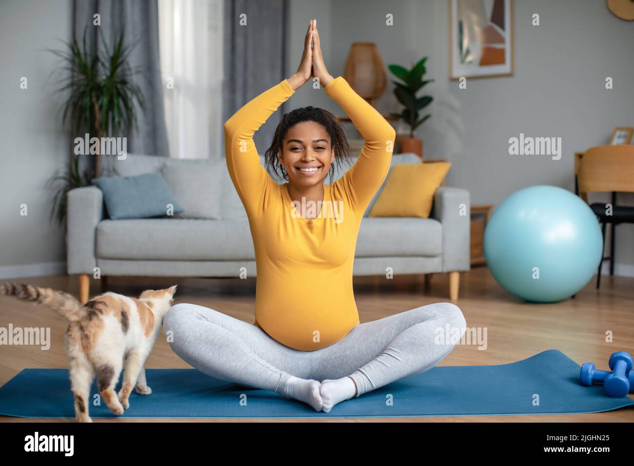 Gaie jeune femme afro-américaine enceinte avec le gros ventre assis à la position de lotus, pratique le yoga Banque D'Images