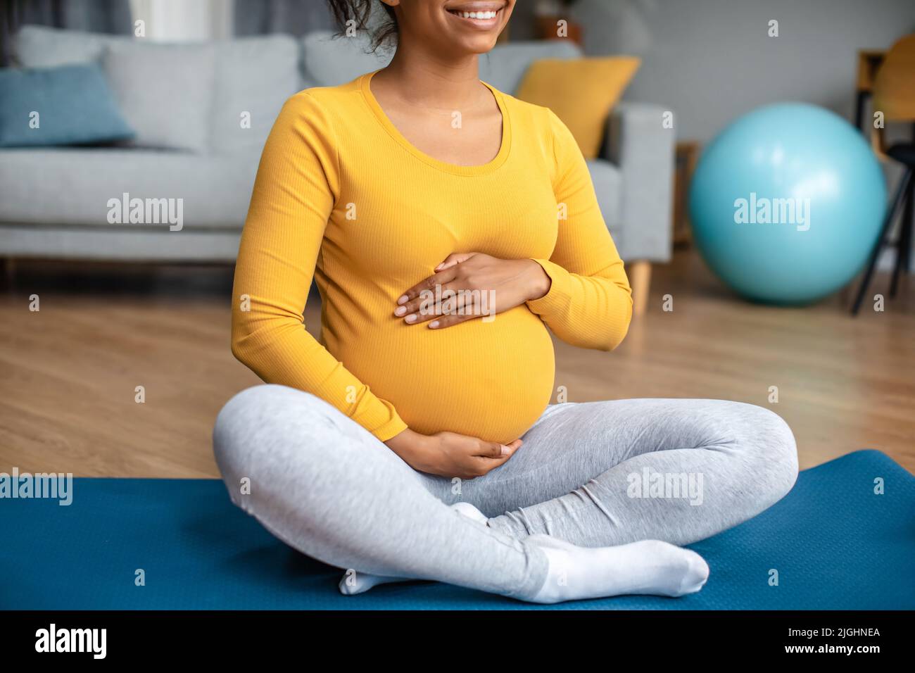 Soins du corps et entraînement. Souriante jeune femme enceinte noire touche le gros ventre, sent le mouvement de bébé Banque D'Images