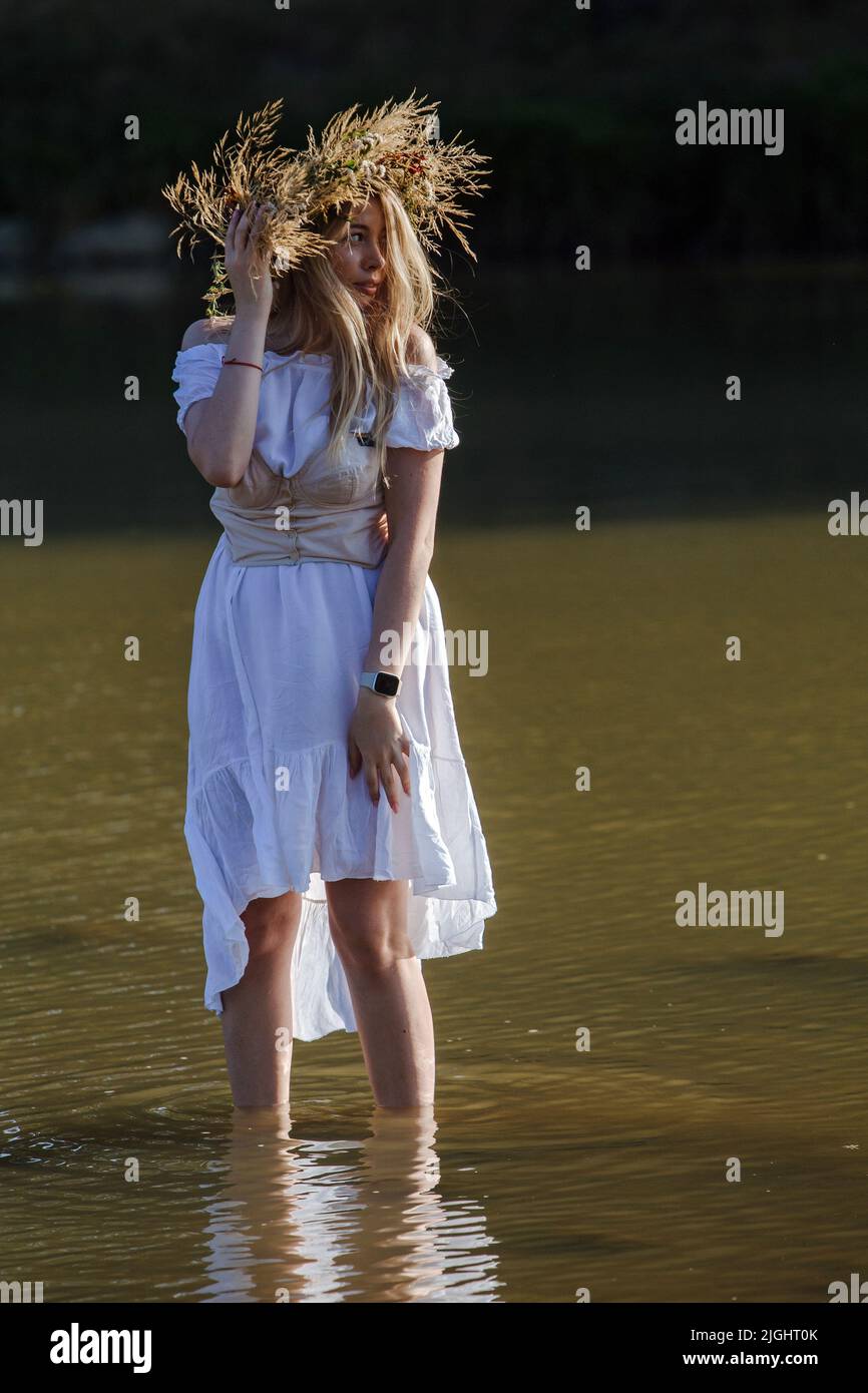 UZHHOROD, UKRAINE - le 8 JUILLET 2022 - Une femme dans une couronne tient à la cheville dans l'eau pendant la célébration de la nuit Kupala organisée par le mouvement pour le TH Banque D'Images