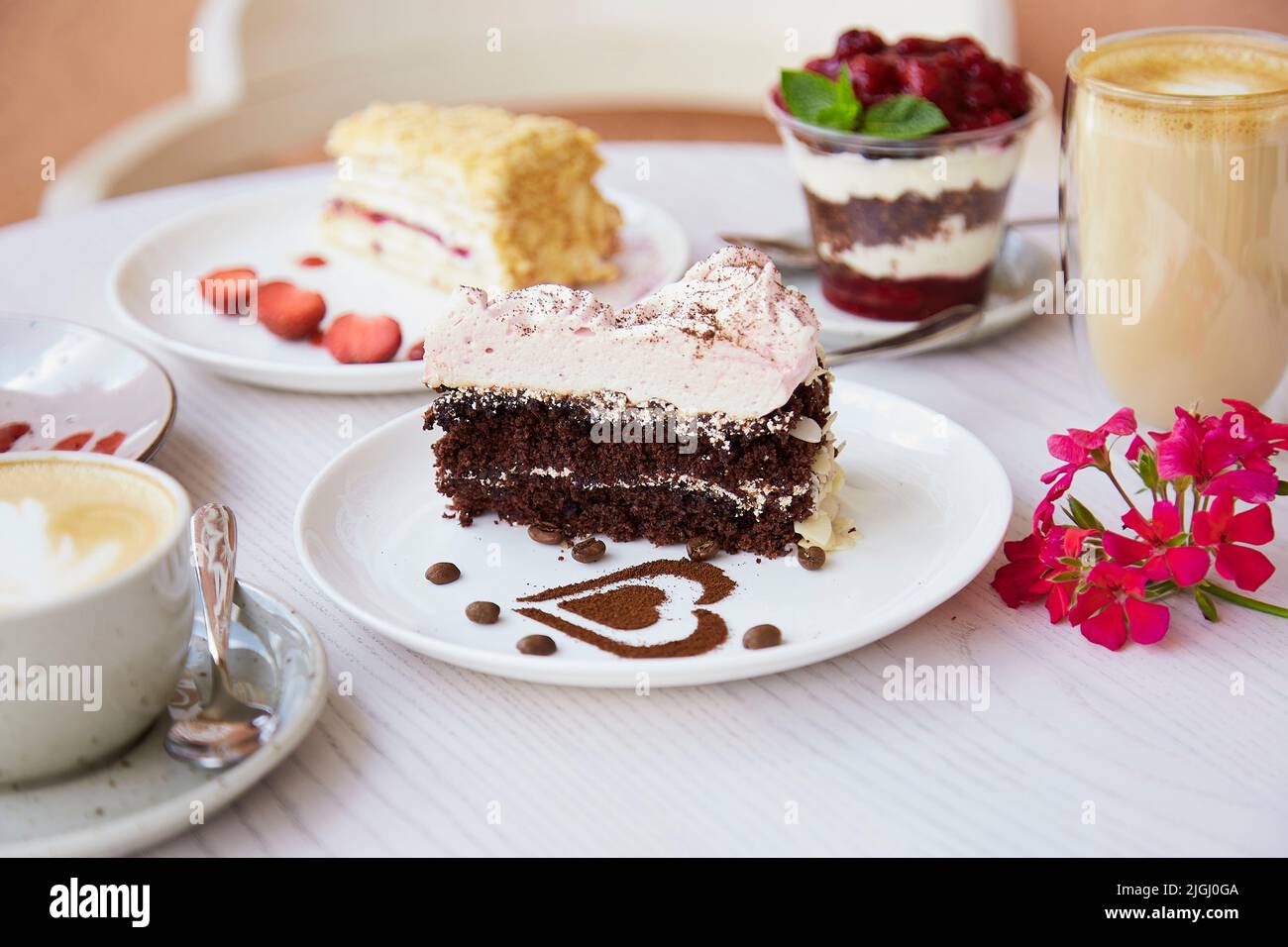 Légumes naturels, desserts superposés, gâteaux aux fruits frais et baies à l'extérieur et verre de Latte. Célébration, assortiment de bonbons sur le ter Banque D'Images