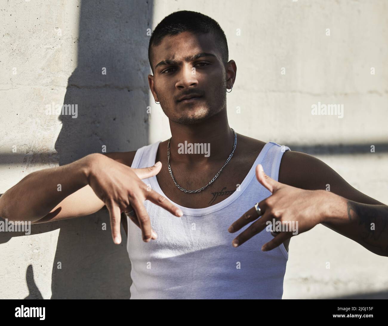 Ce qui est bien dans le capot. Portrait d'un jeune homme montrant des signes de gang sur un fond urbain. Banque D'Images
