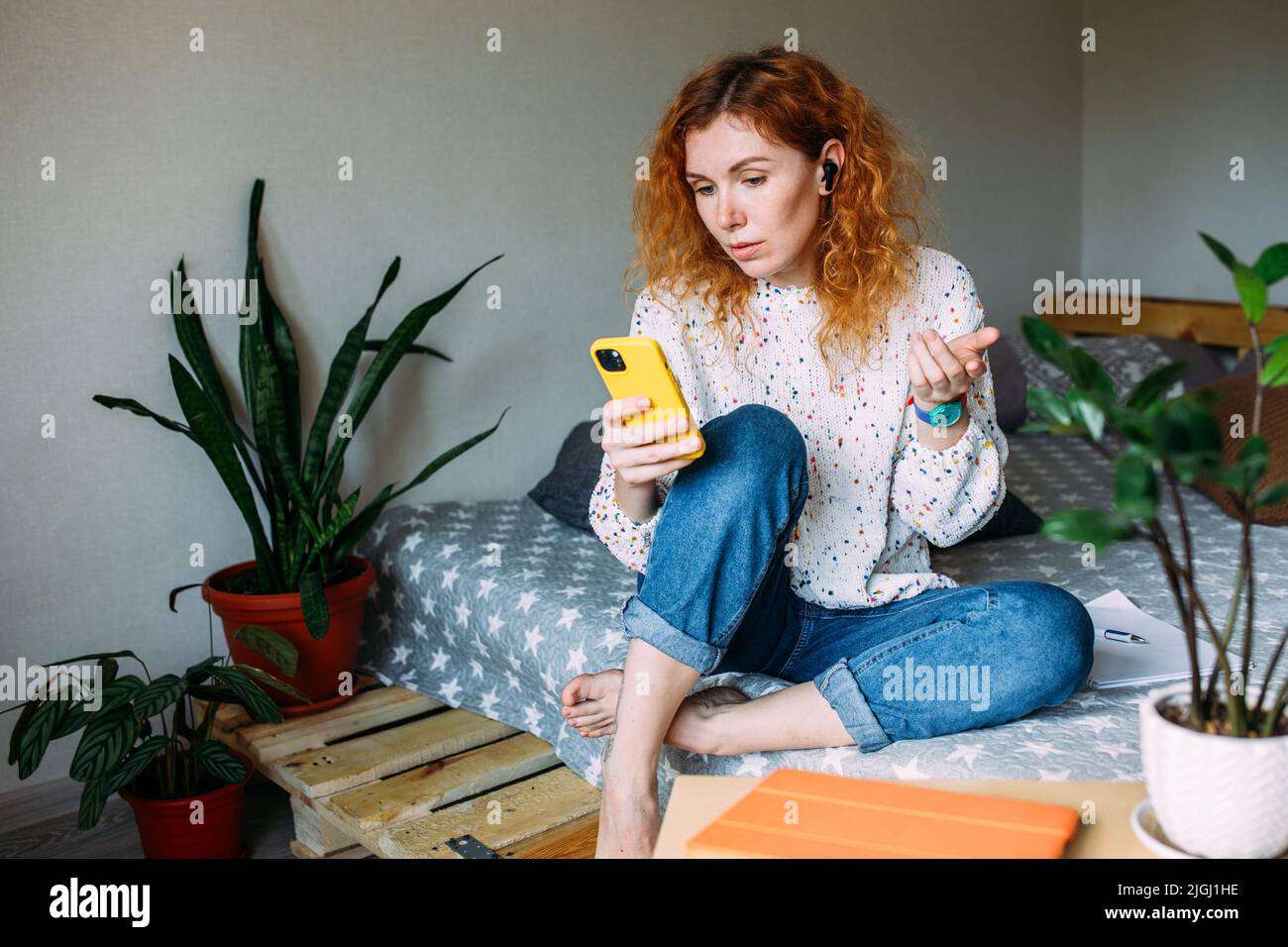 Jeune femme parlant sur un smartphone depuis sa maison lors d'un appel vidéo Banque D'Images