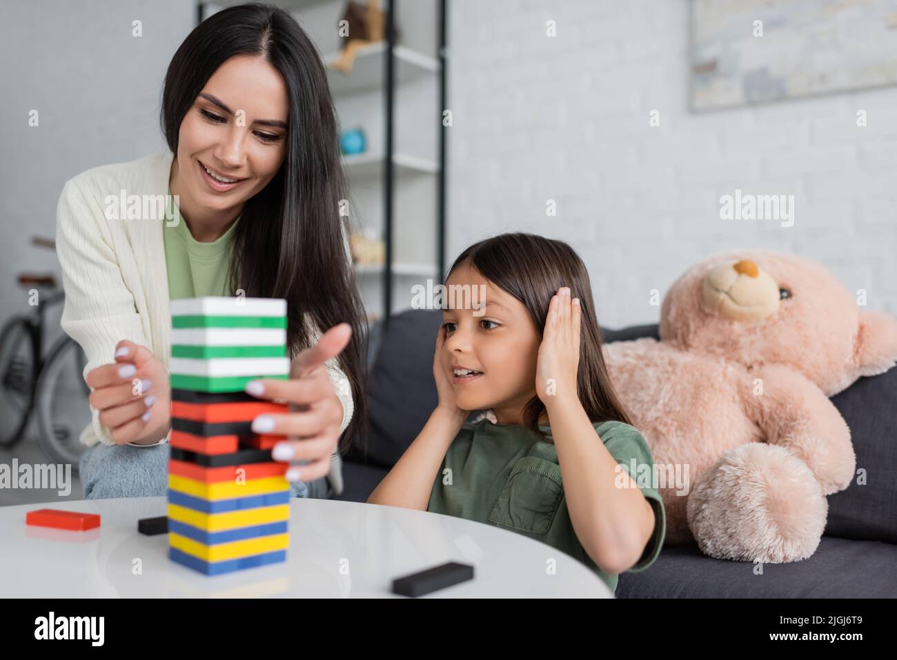 bonne baby-sitter jouer à des blocs de bois jeu avec fille souriante dans le salon Banque D'Images