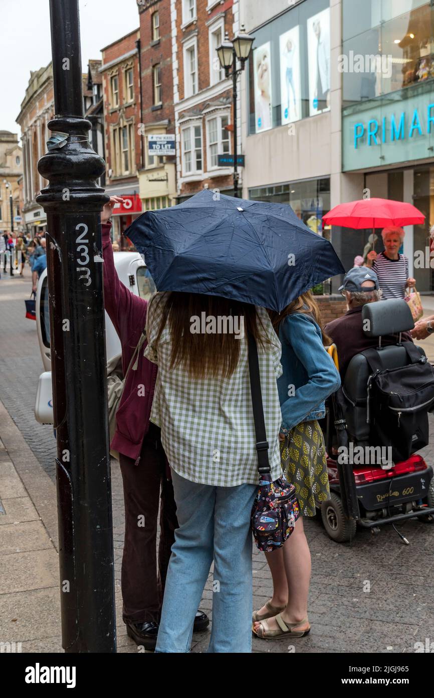 Trois femmes parlent ensemble sous un parapluie à ciel ouvert High Street Lincoln City 2022 Banque D'Images