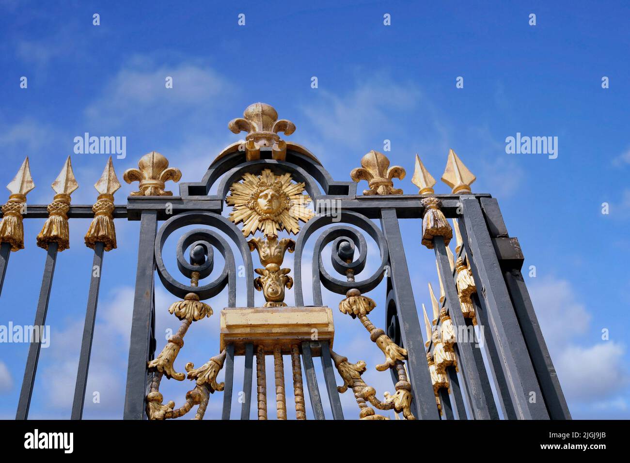 Clôture dorée à l'ancien palais royal de Versailles, avec Louis XIV représenté comme le Roi Soleil Banque D'Images