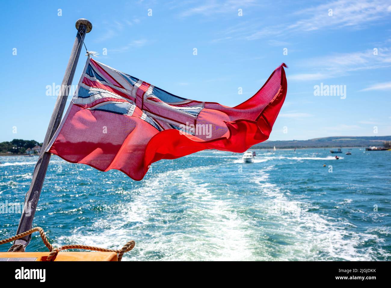 Drapeau rouge soufflant dans le vent sur la poupe d'un bateau Banque D'Images