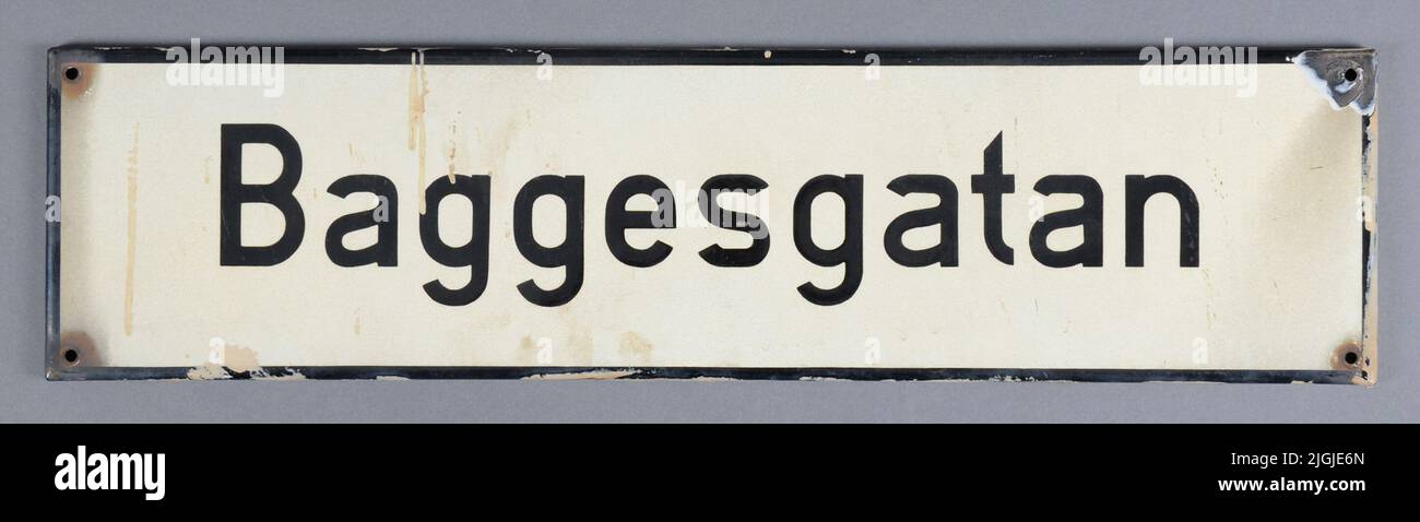 Panneau de Gatoskylt, panneau de rue de tôle. Rectangulaire, émaillé. Blanc avec cadre noir et texte « Baggesgatan ». Quatre trous pour le montage.peinture beige sur les bords de la peinture de façade. L'émail est endommagé dans un coin. Ajouté au 1966-11-18, lors de la démolition de la propriété Varvsgatan 33, kV Drottninghall 11, Karlskrona. Banque D'Images