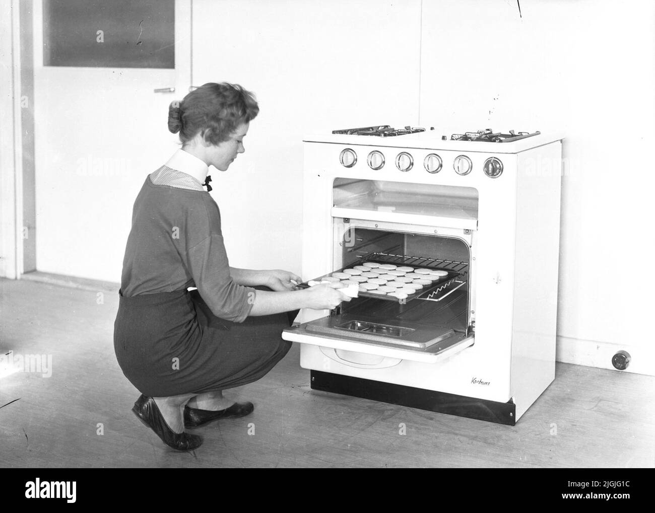 Une femme se fait cuire des biscuits dans les cuisines d'essai. Banque D'Images
