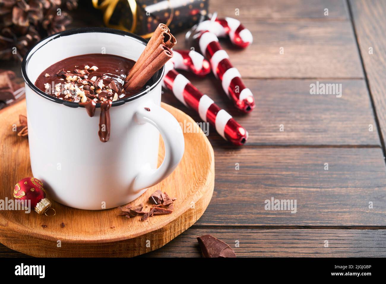 Chocolat chaud. Chocolat chaud épicé maison à la cannelle, noisette écrasée, décoration de noël et jouets en mug en émail sur fond de bois ancien. Christma Banque D'Images