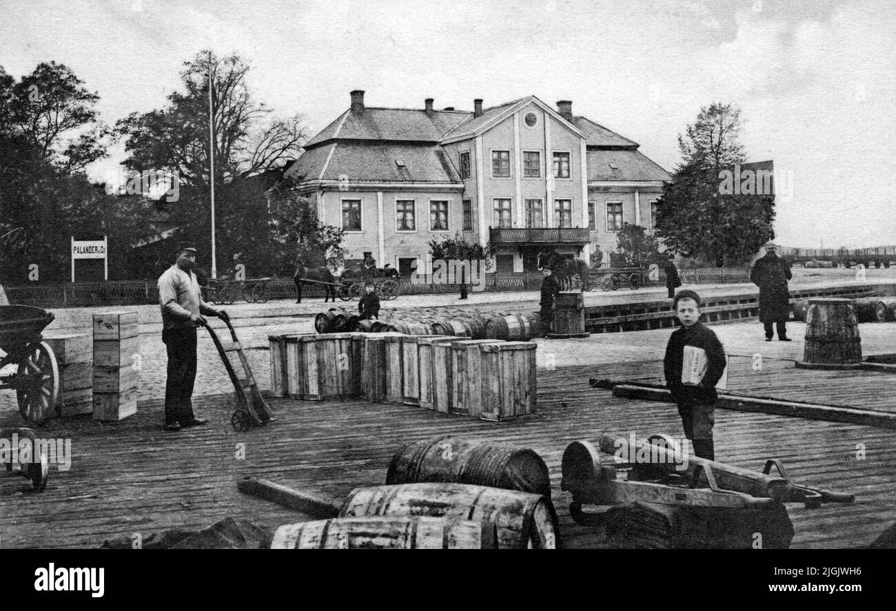 Gård hommes qui travaillent avec des boîtes de chargement et des barils sur le pont de Stockholm sous la ferme de Palander dans le port commercial. Banque D'Images