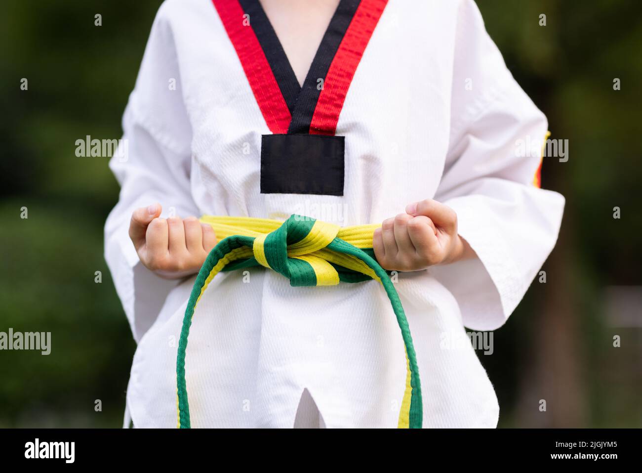 Petite fille caucasienne de sept ans dans un kimono avec ceinture verte  jaune faisant de l'exercice de Taekwondo au parc d'été seul pendant le  verrouillage du coronavirus covid-19 Photo Stock - Alamy