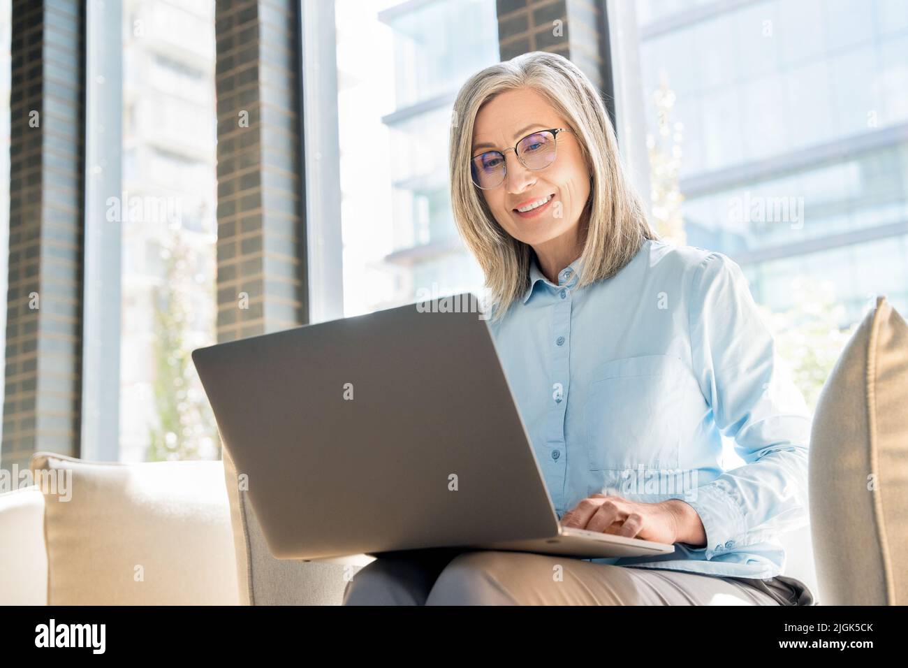 Femme senior travaille comme freelance sur ordinateur portable dans un collègue. Banque D'Images