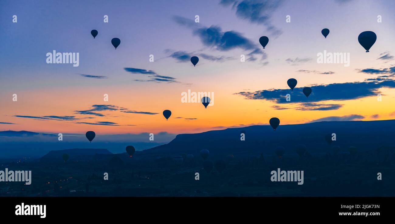 Des ballons à air chaud survolent au lever du soleil la ville de Goreme en Turquie. Banque D'Images