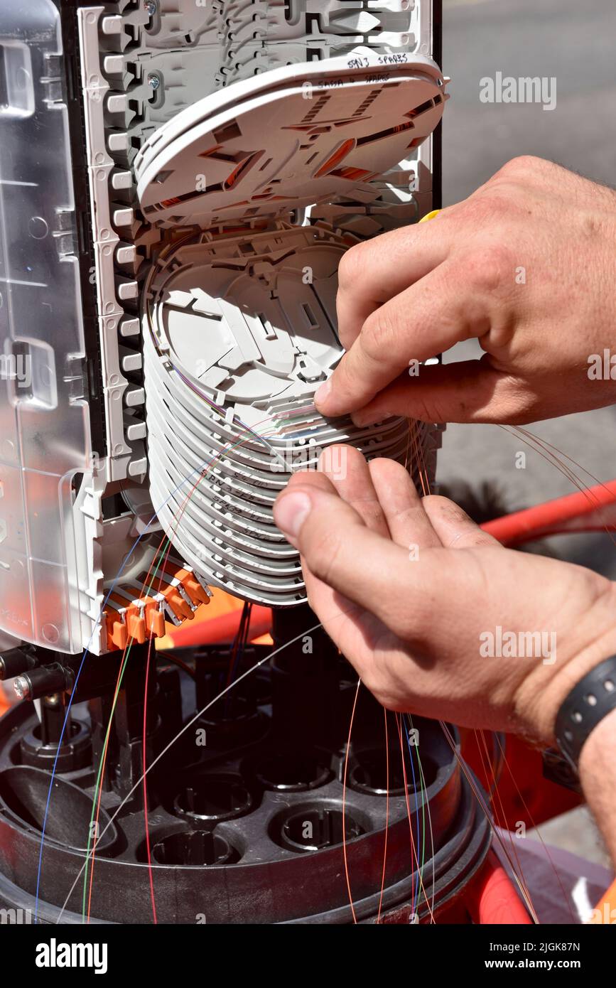 Ingénieur installant des fibres dans le boîtier de distribution de câblage de fibre optique dans la rue pour le haut débit et le téléphone, en donnant la fibre à la maison Banque D'Images