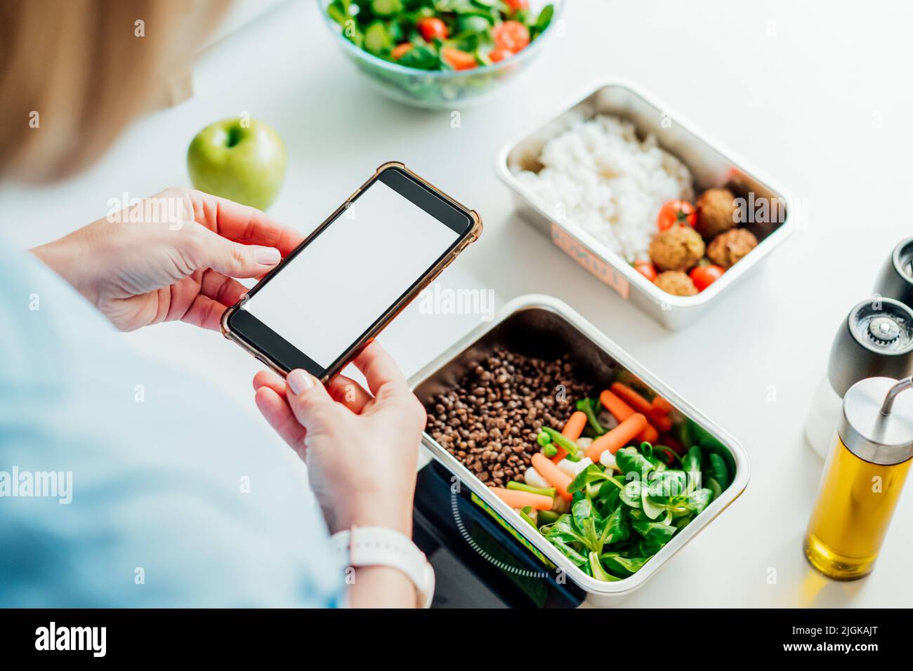 Régime alimentaire sain pour la perte de poids, menu quotidien prêt à manger. Femme utilisant un téléphone avec écran vide pour l'application tout en pesant la boîte repas cuit à l'avance sur ki Banque D'Images Régime alimentaire sain pour la perte de poids, menu quotidien prêt à manger. Femme utilisant un téléphone avec écran vide pour l'application tout en pesant la boîte repas cuit à l'avance sur ki Banque D'Images