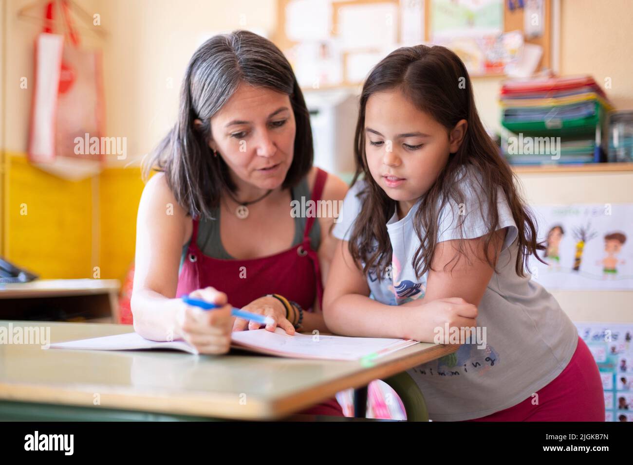 Une jeune femme enseignante aide un élève de l'école primaire en classe à apprendre une leçon. Concept d'éducation et de développement des enfants. Banque D'Images