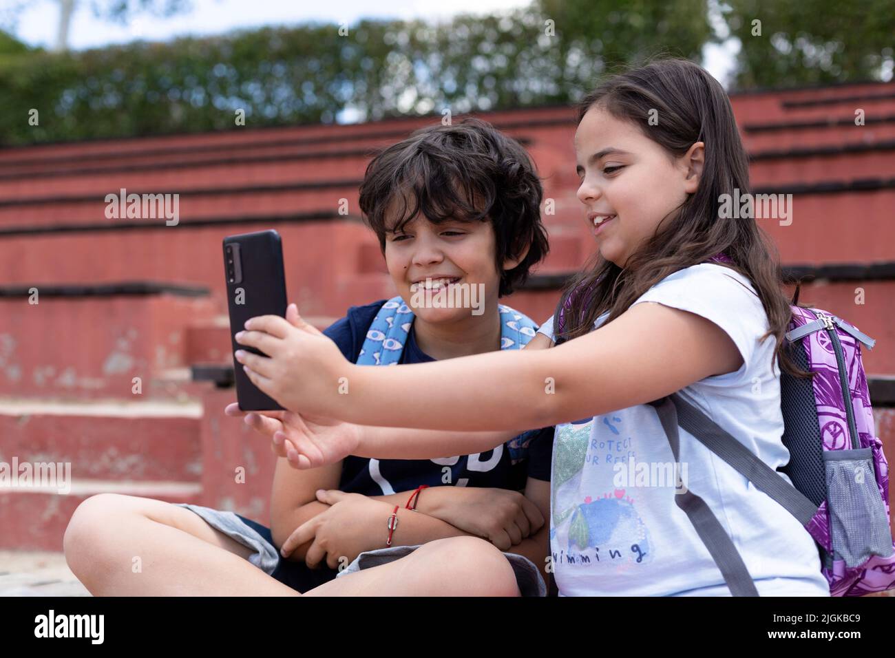 Souriant des jeunes filles et des garçons de l'école élémentaire du caucase prenant une photo avec un smartphone avant d'aller en classe. Retour à l'école. Banque D'Images