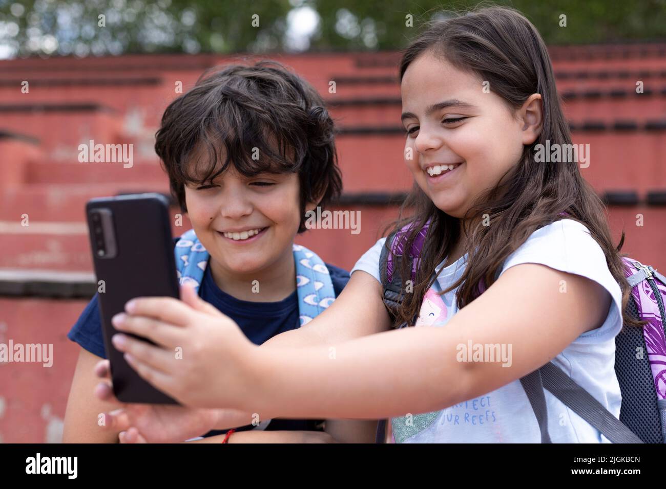 Gros plan des jeunes filles et garçons du caucase souriants qui prennent une photo avec un téléphone portable à l'extérieur. Concept de l'utilisation de la technologie Banque D'Images