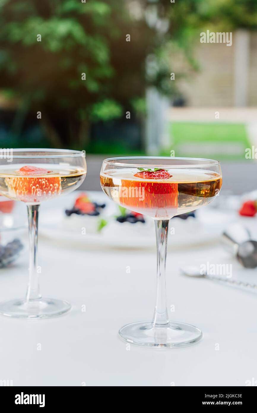 Cocktails avec fraises fraîches et gâteaux de Pavlova à la meringue floue avec fraises fraîches et bleuets sur fond de jardin. Desserts et Banque D'Images