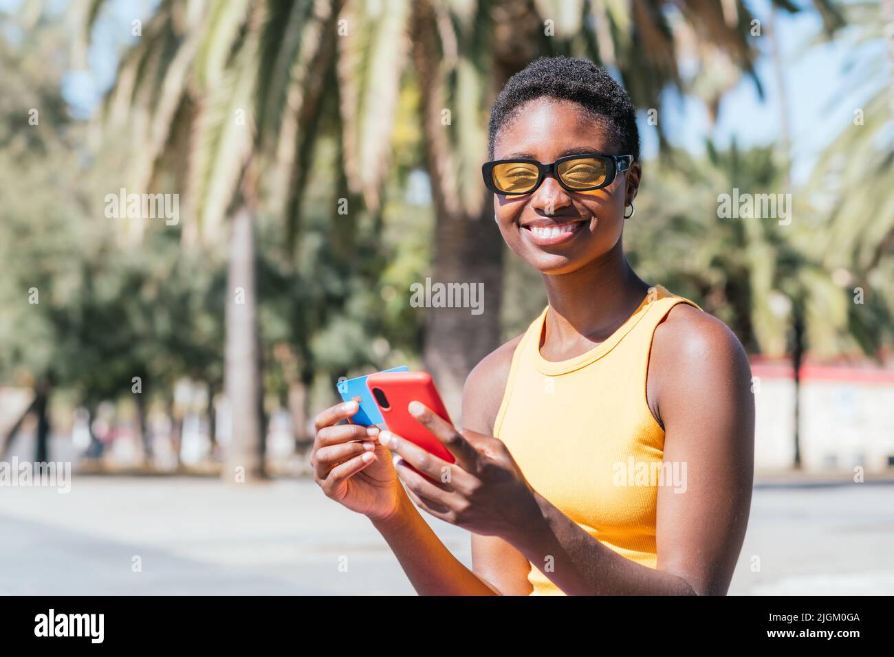 bonne femme afro-américaine utilisant son téléphone et sa carte de crédit dans la rue Banque D'Images